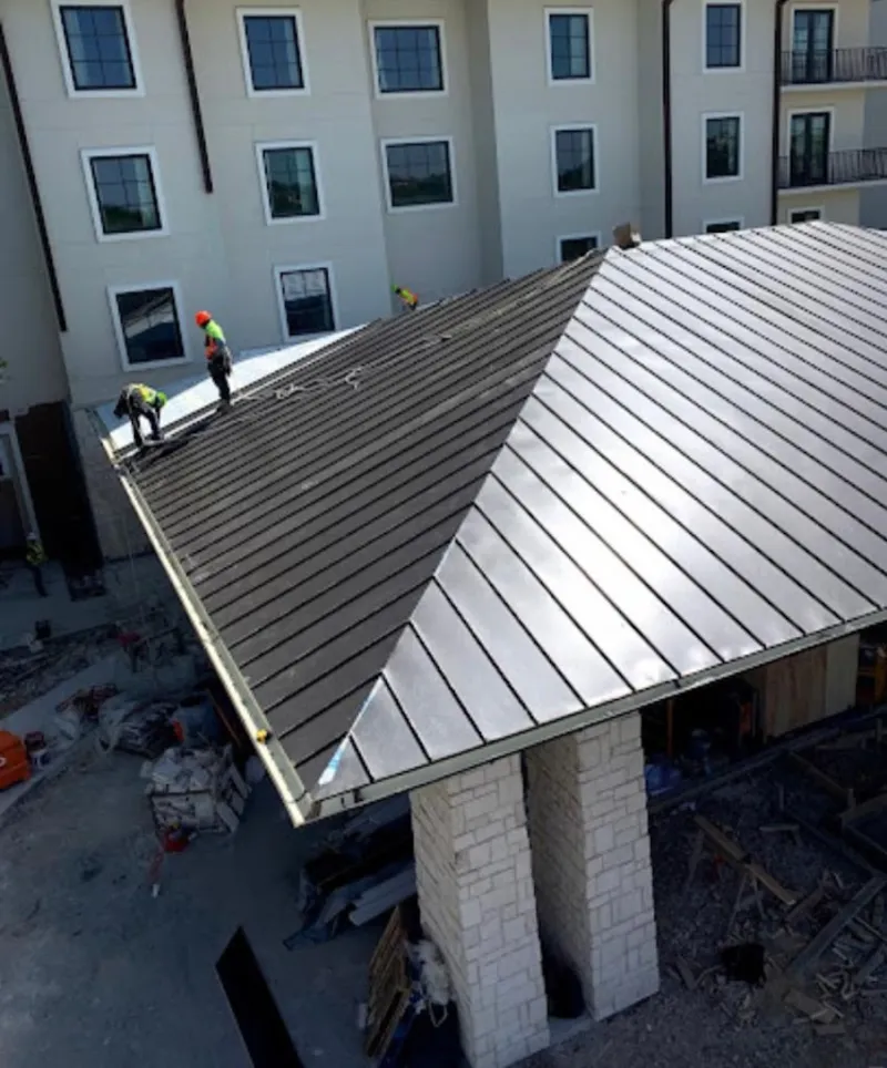 Crew installing standing seam metal roof panels on a commercial project in Attalla